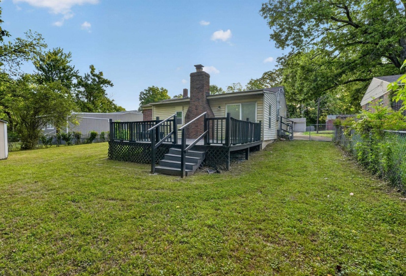 Back of property featuring a fenced backyard, a wooden deck, and a chimney