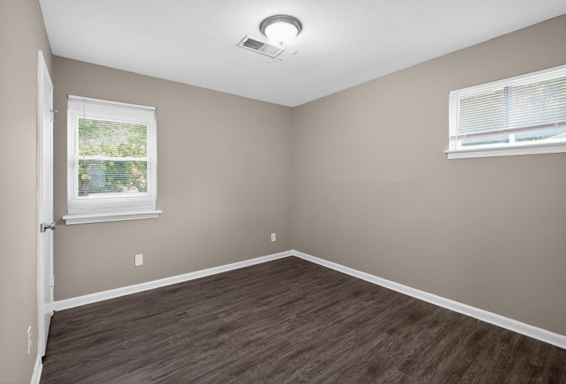 Unfurnished room featuring baseboards and dark wood-style flooring