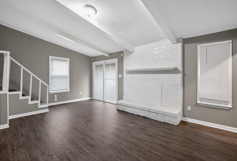 Unfurnished living room featuring dark wood-style flooring, a fireplace, and beam ceiling