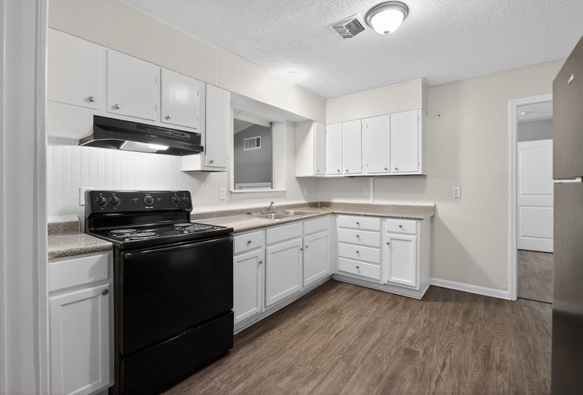 Kitchen featuring electric range, white cabinets, dark wood-type flooring, a textured ceiling, and light countertops