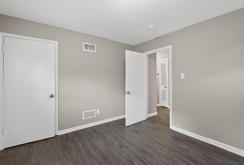 Unfurnished bedroom with baseboards and dark wood-type flooring