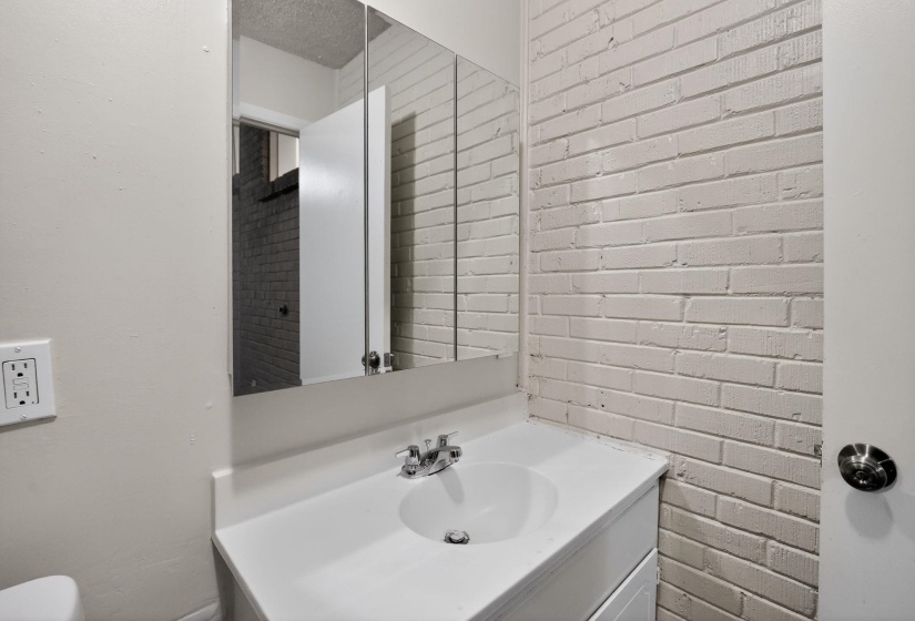 Bathroom featuring vanity and brick wall