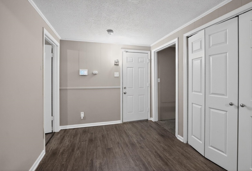 Hall with a textured ceiling, crown molding, and dark wood finished floors