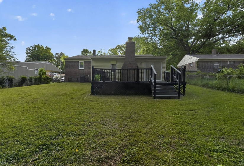 Back of house featuring a chimney, a deck, and brick siding