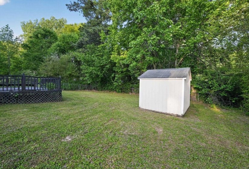 Fenced backyard featuring a storage shed and a deck
