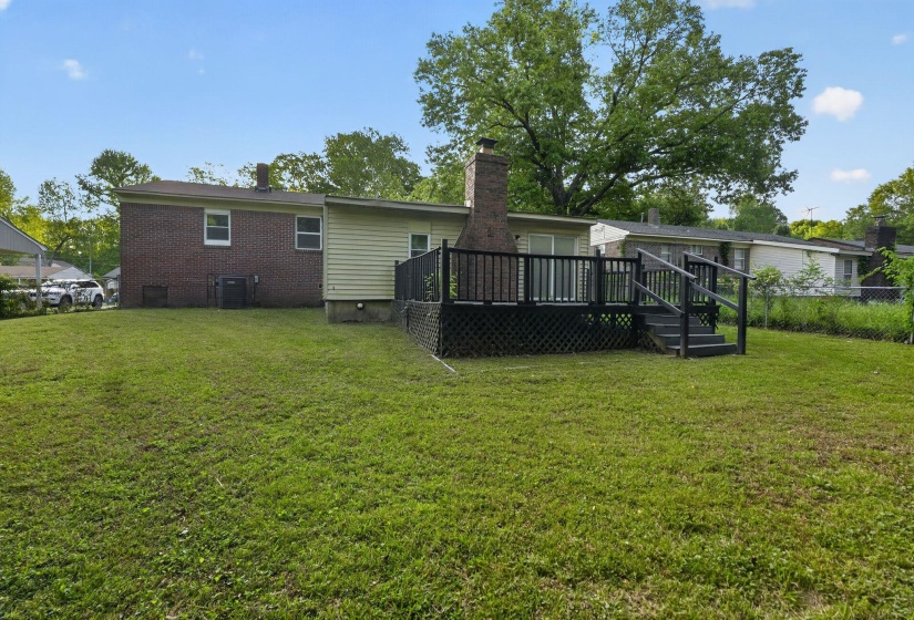 Rear view of property featuring a wooden deck, a chimney, and brick siding