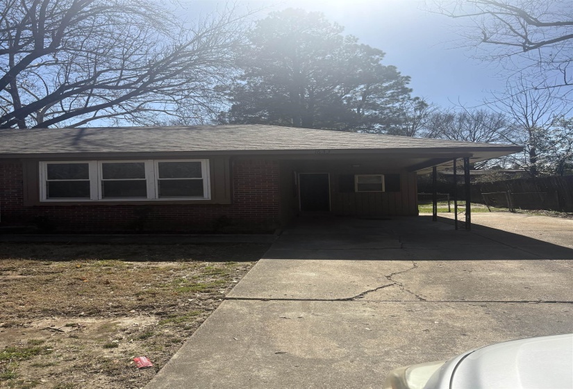 View of front of house featuring concrete driveway, a carport, brick siding, and a shingled roof