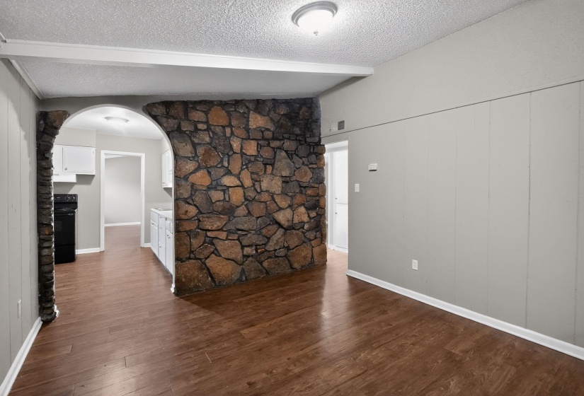 Unfurnished room with arched walkways, dark wood-type flooring, and a textured ceiling