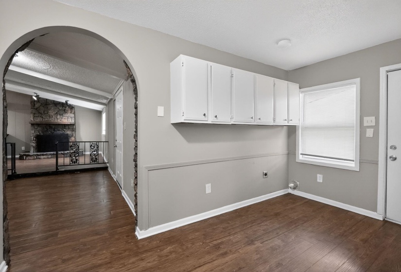 Laundry area with dark wood-style floors, a fireplace, arched walkways, and electric dryer hookup