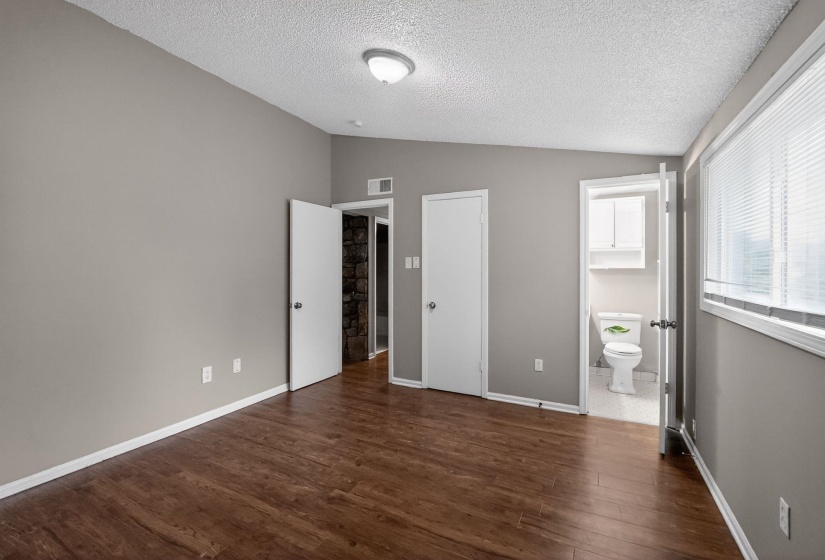 Unfurnished bedroom featuring dark wood finished floors and ensuite bath