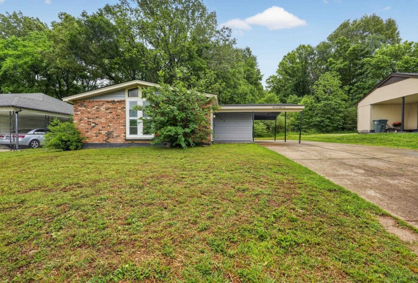Mid-century home featuring a front lawn, a carport, driveway, and brick siding