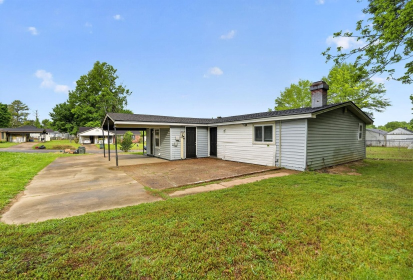 View of front of home featuring a front yard, a carport, and a chimney