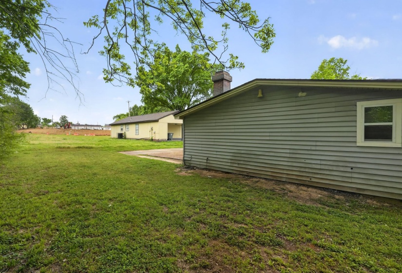 View of side of home featuring a lawn and a chimney