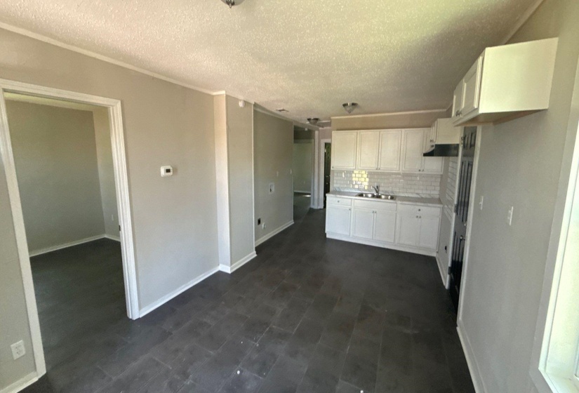 Kitchen featuring light countertops, a textured ceiling, decorative backsplash, and white cabinets