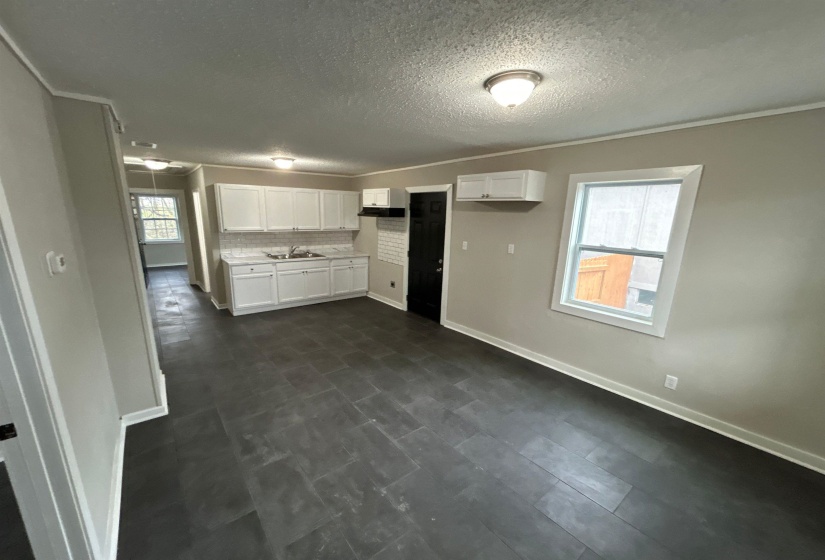 Kitchen featuring white cabinetry, light countertops, ornamental molding, decorative backsplash, and a textured ceiling