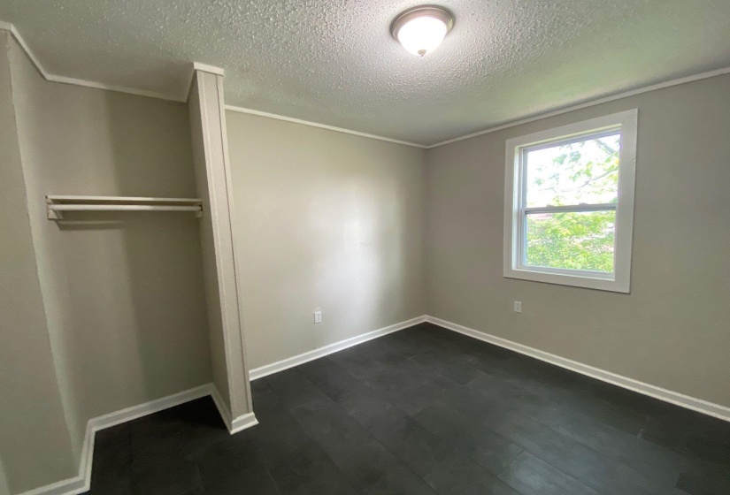 Unfurnished bedroom with a textured ceiling, a closet, and crown molding