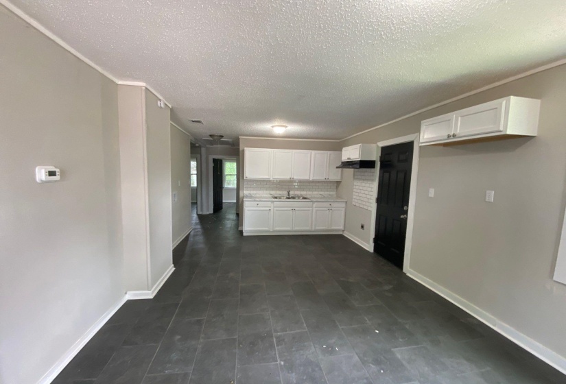 Kitchen featuring white cabinetry, light countertops, ornamental molding, decorative backsplash, and a textured ceiling