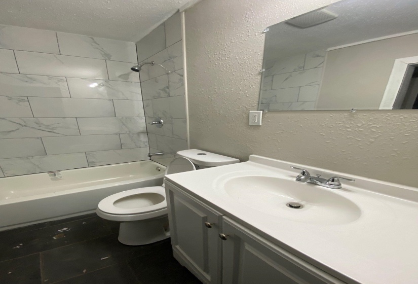 Bathroom featuring a textured wall, a textured ceiling, vanity, and shower / bath combination