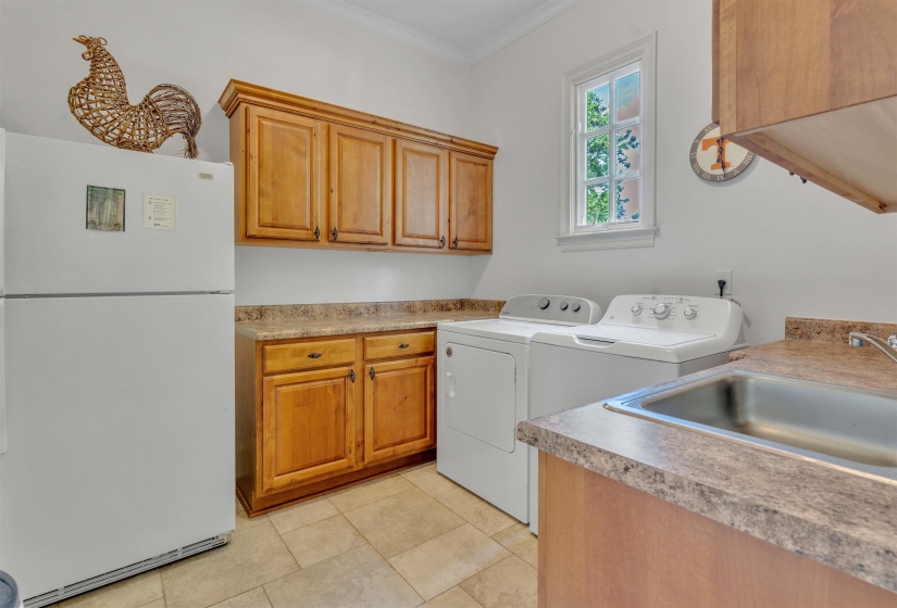 Laundry area with ornamental molding, washing machine and clothes dryer, light tile patterned floors, and cabinet space