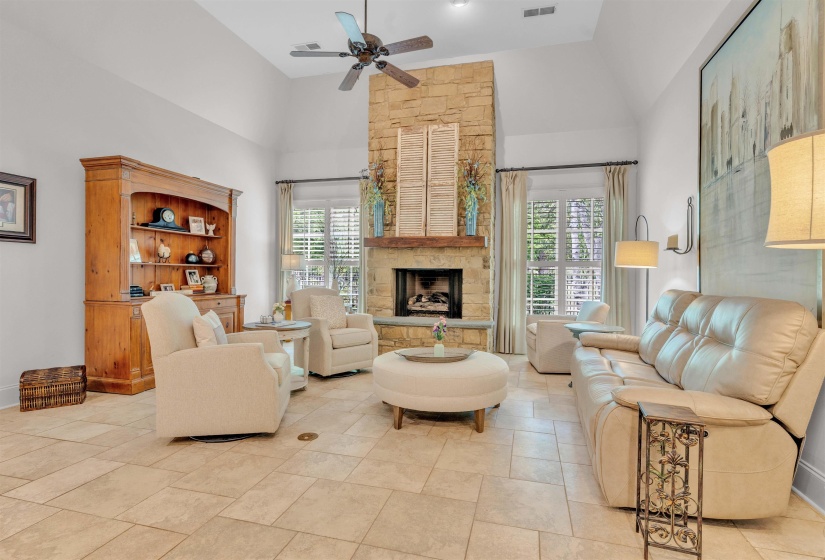 Living room with a ceiling fan, a fireplace, and vaulted ceiling