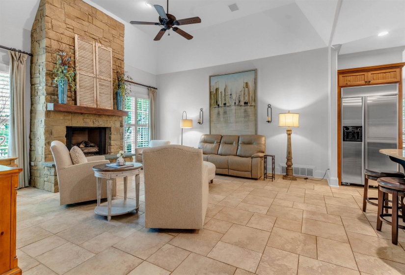 Living room featuring ceiling fan, a stone fireplace, a high ceiling, and recessed lighting
