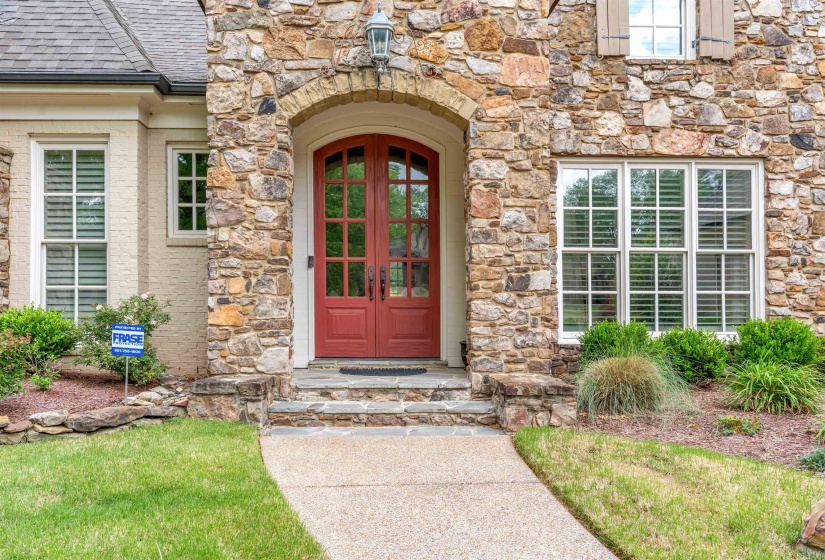 Entrance to property with stone siding, french doors, and roof with shingles