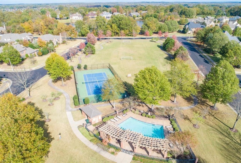 Community amenities featuring a swimming pool with pergola, tennis court, and expansive green space