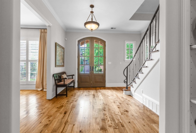 Foyer entrance with light wood-style flooring, french doors, and crown molding