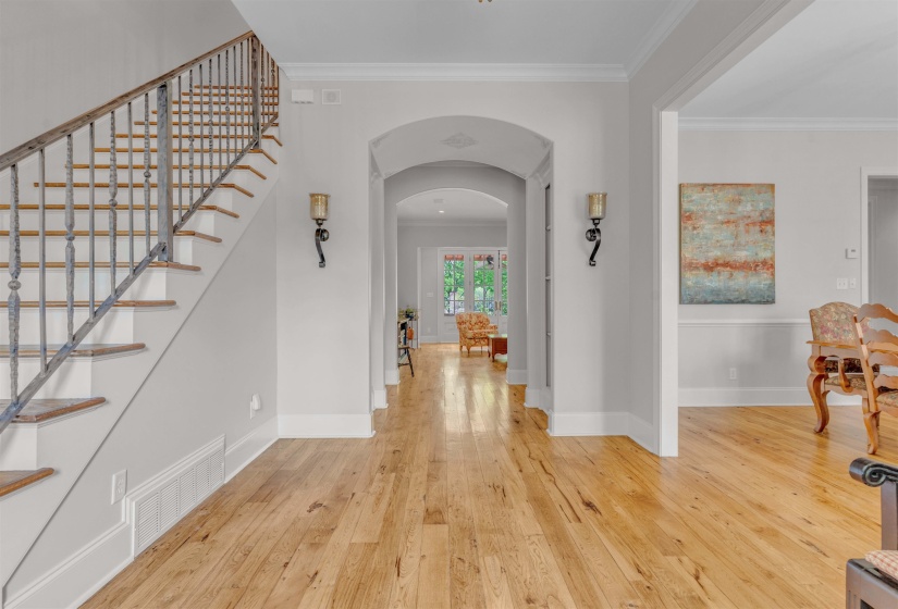 Foyer with arched walkways, light wood-style floors, and ornamental molding