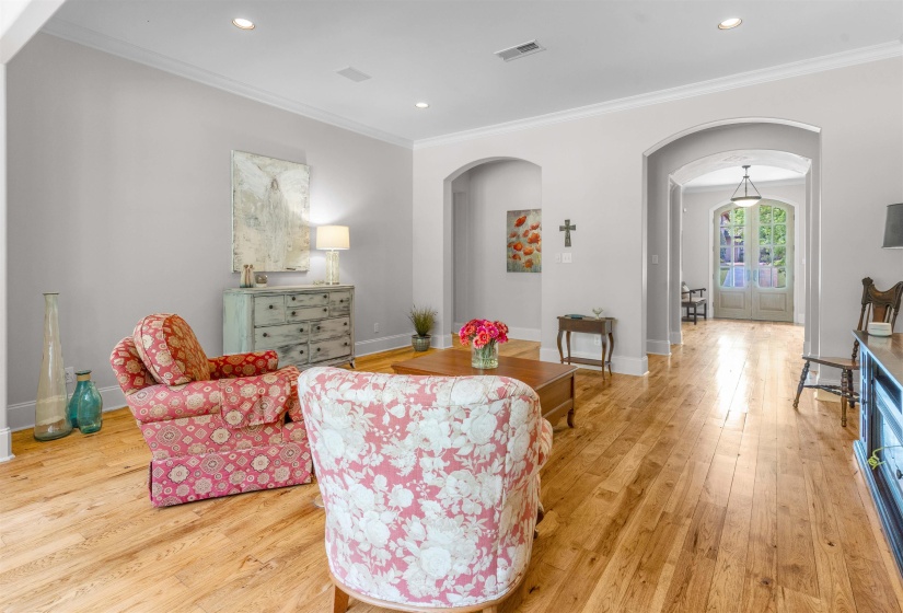 Living room with arched walkways, ornamental molding, light wood-style floors, and recessed lighting
