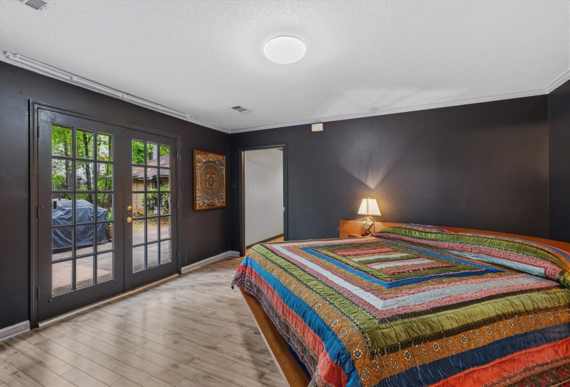 PRIMARY BEDROOM (15 x 14) with LVP flooring and double doors opening to  the Backyard for a peaceful retreat.