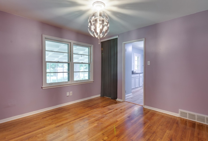 Hardwood flooring, a modern ceiling light fixture, and a window with white trim