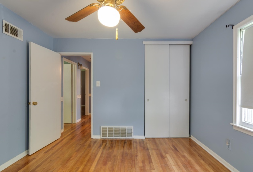 Interior room featuring wood-finish flooring, a ceiling fan with integrated lighting, and a white sliding door closet