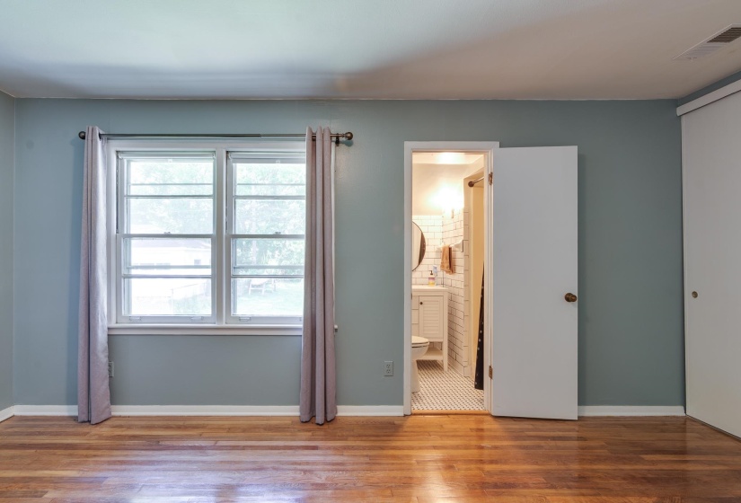 Hardwood flooring throughout featuring a double-pane window, white baseboards, and a neutral wall color