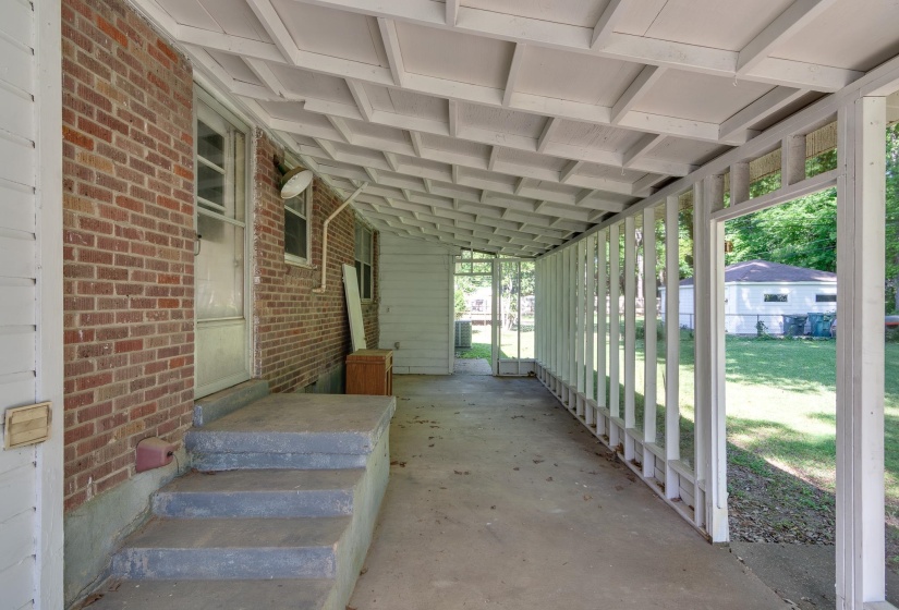 Covered porch with exposed brick wall and concrete flooring