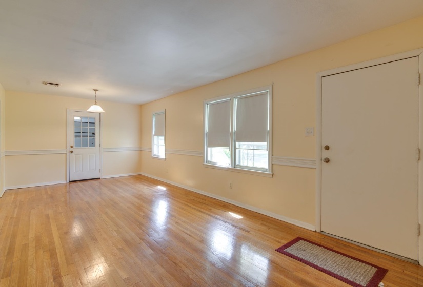 Hardwood flooring extends throughout this room, featuring light cream walls with white chair rail molding