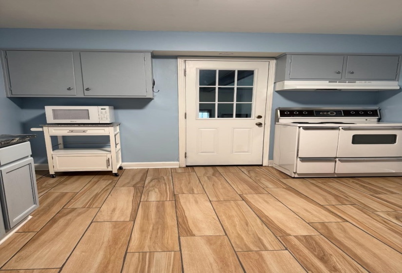 Kitchen featuring wood-finish plank tile flooring, light blue painted walls, and light gray cabinetry