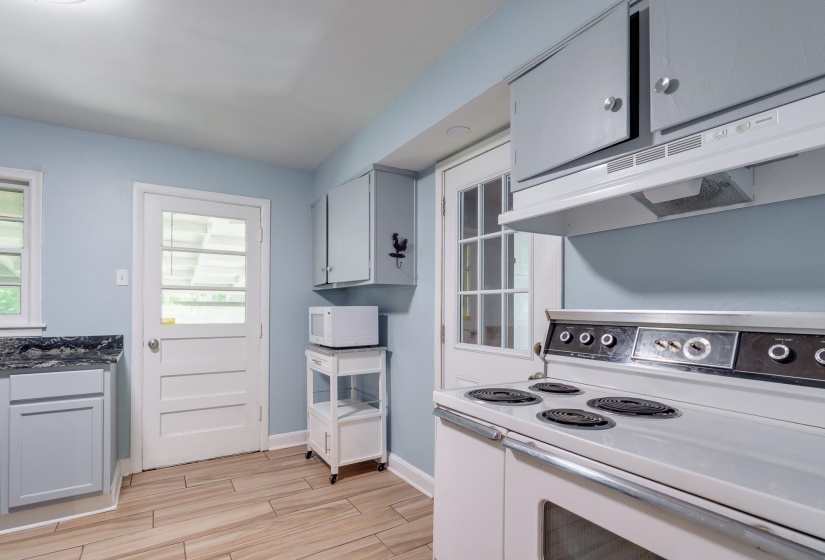 Kitchen featuring a built-in range with an overhead vent, light wood-finish flooring, light blue walls, and grey cabinetry