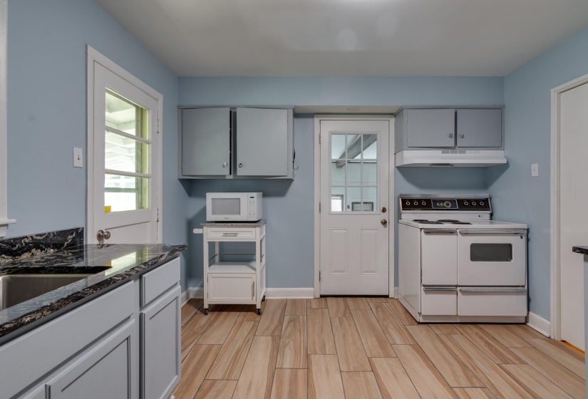 Kitchen featuring wood-finish flooring, light blue walls, gray cabinetry, and dark countertop surfaces