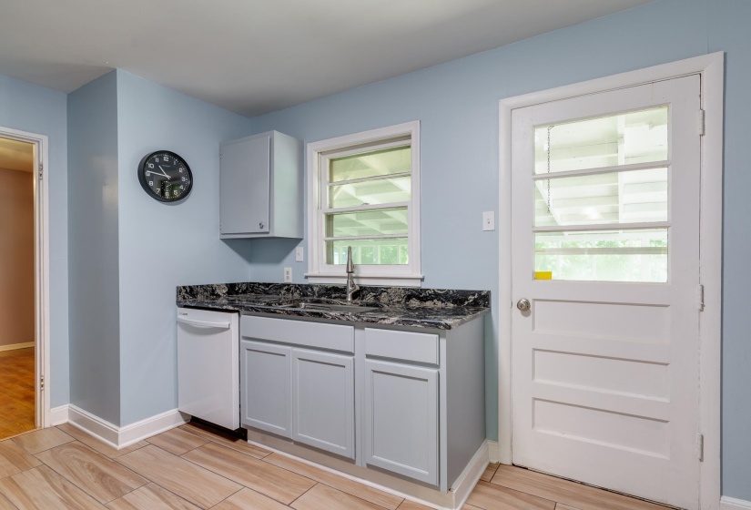 Kitchenette featuring a stainless steel sink, dark granite countertop, and light gray cabinetry