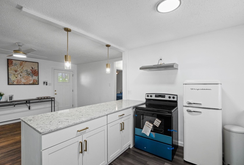 Kitchen featuring white shaker cabinetry, light-toned countertops, modern pendant lighting, a built-in range, and a retro-style refrigerator