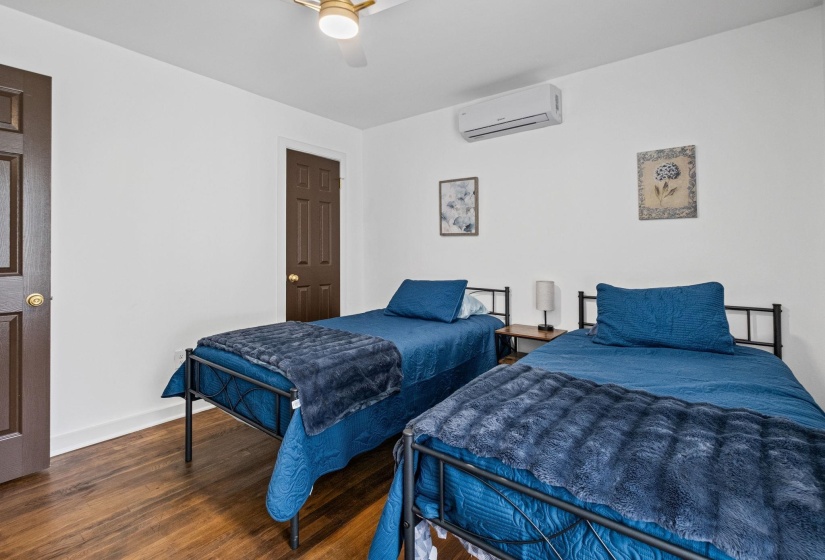 Bedroom featuring wood-finish flooring, white walls, and a ceiling fan