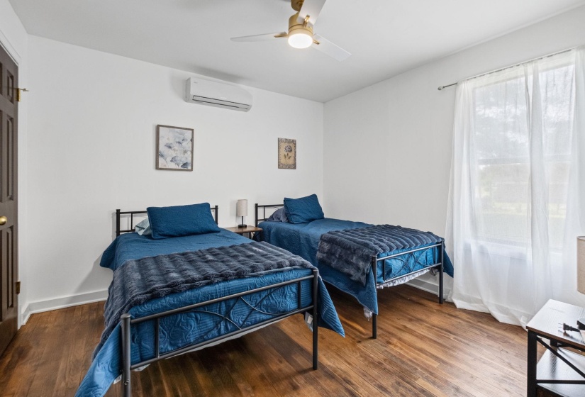 Room featuring wood-finish flooring, white walls, and a ceiling fan with integrated lighting