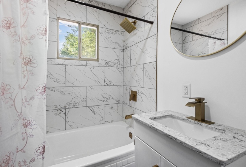 Bathroom featuring a white vanity with an integrated sink, a speckled countertop, and a brass-finish faucet