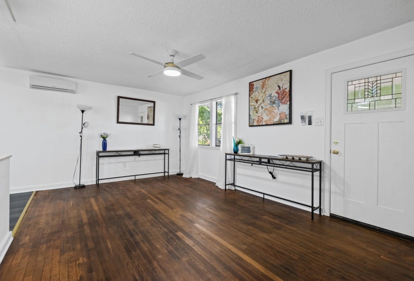 Expansive room featuring rich wood-finish flooring, white walls, and a ceiling fan with integrated lighting