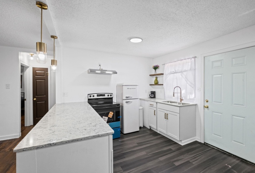 Kitchen featuring white cabinetry, light-toned countertops, a stainless steel sink with a gooseneck faucet, black electric range, and wood-finish flooring