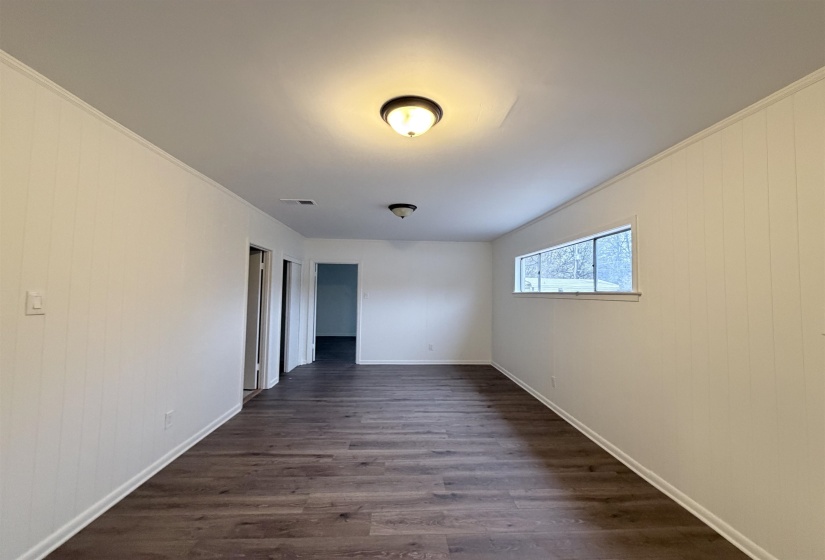 Unfurnished room featuring dark wood-type flooring, wood walls, and ornamental molding