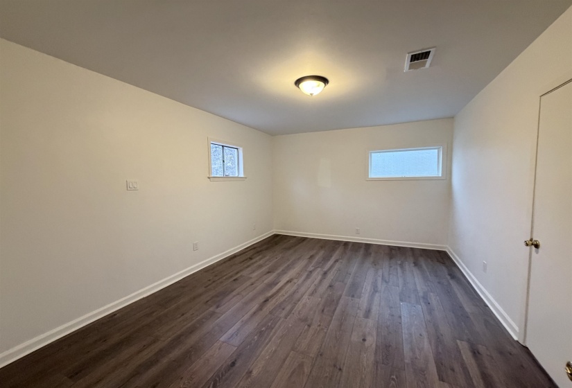 Spare room featuring dark wood-type flooring and baseboards