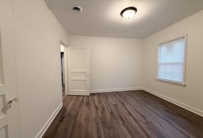 Empty room with dark wood-style floors and crown molding