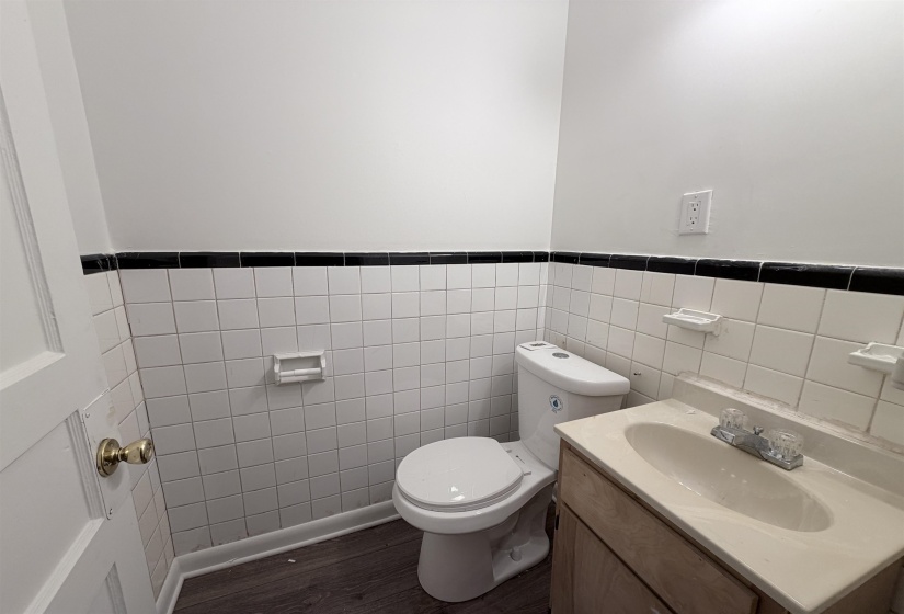 Half bath with vanity, tile walls, dark wood-style floors, and a wainscoted wall